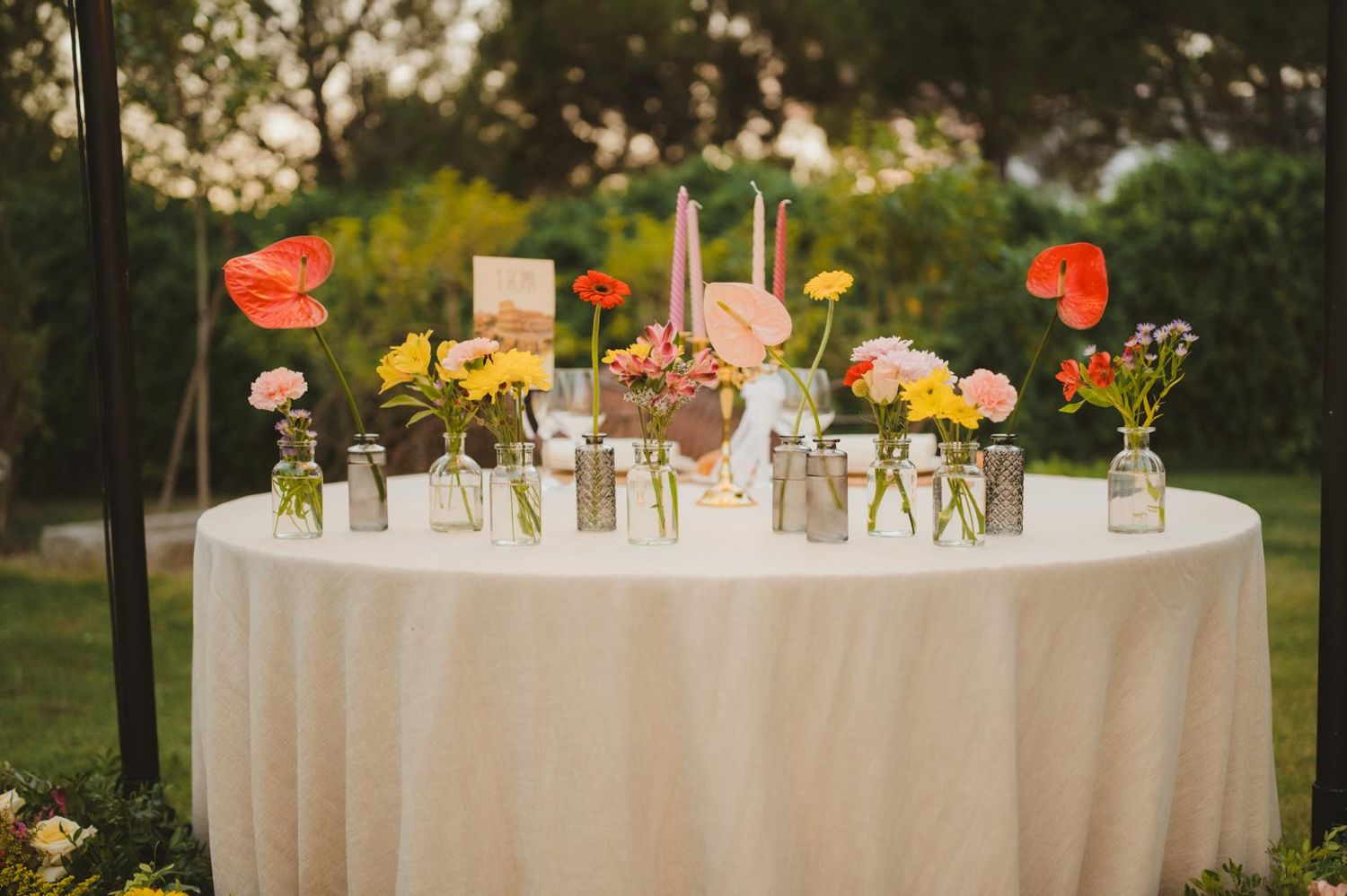 Mesa redonda con jarrones pequeños de flores de colores