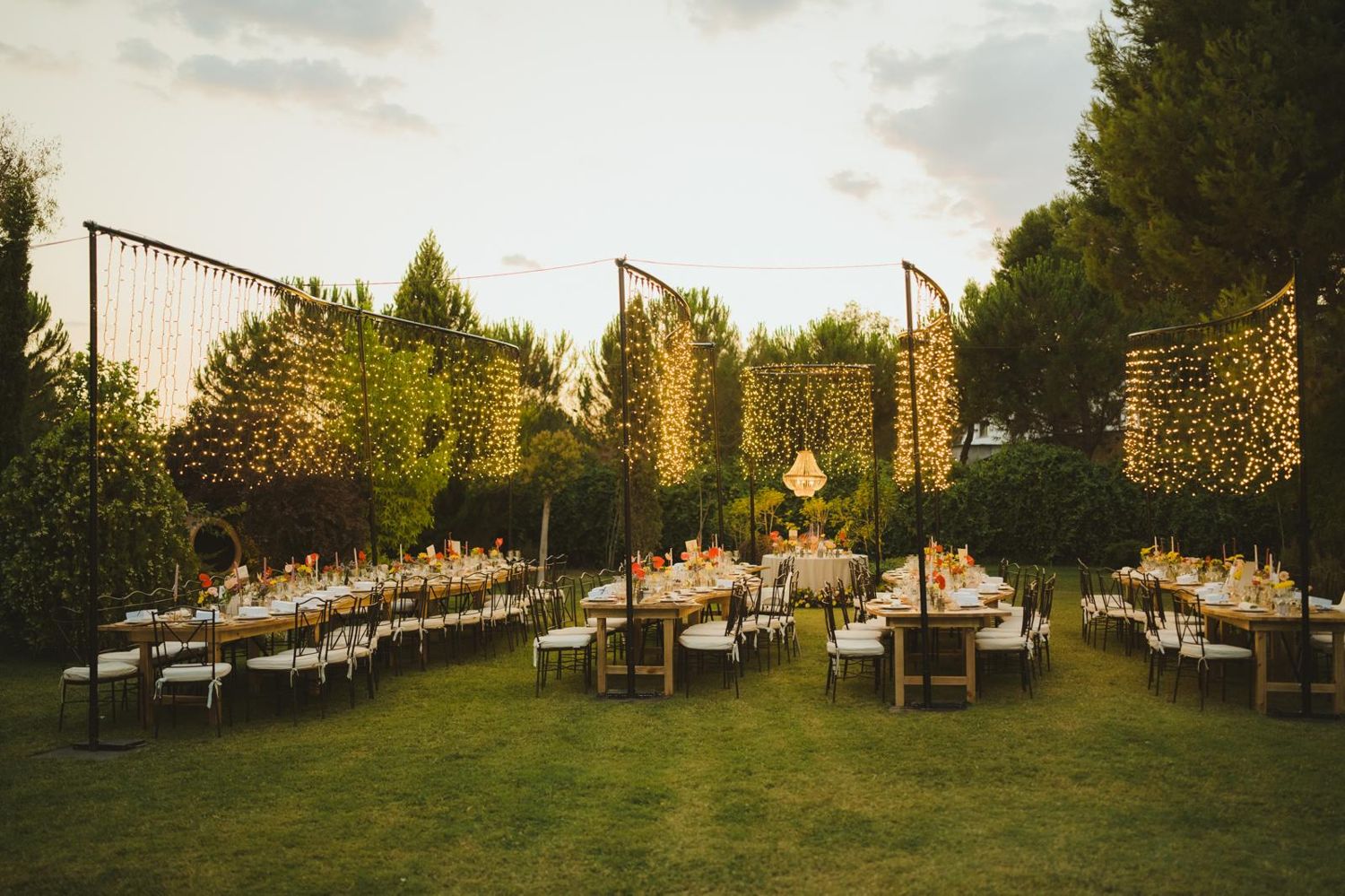 Jardín con mesas y cortinas de luz al atardecer