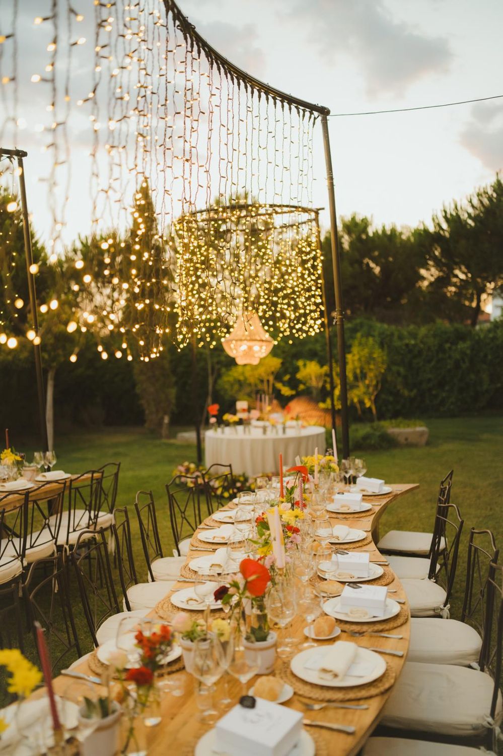 Mesa de novios bajo una lámpara de cristal y una cortina de luces