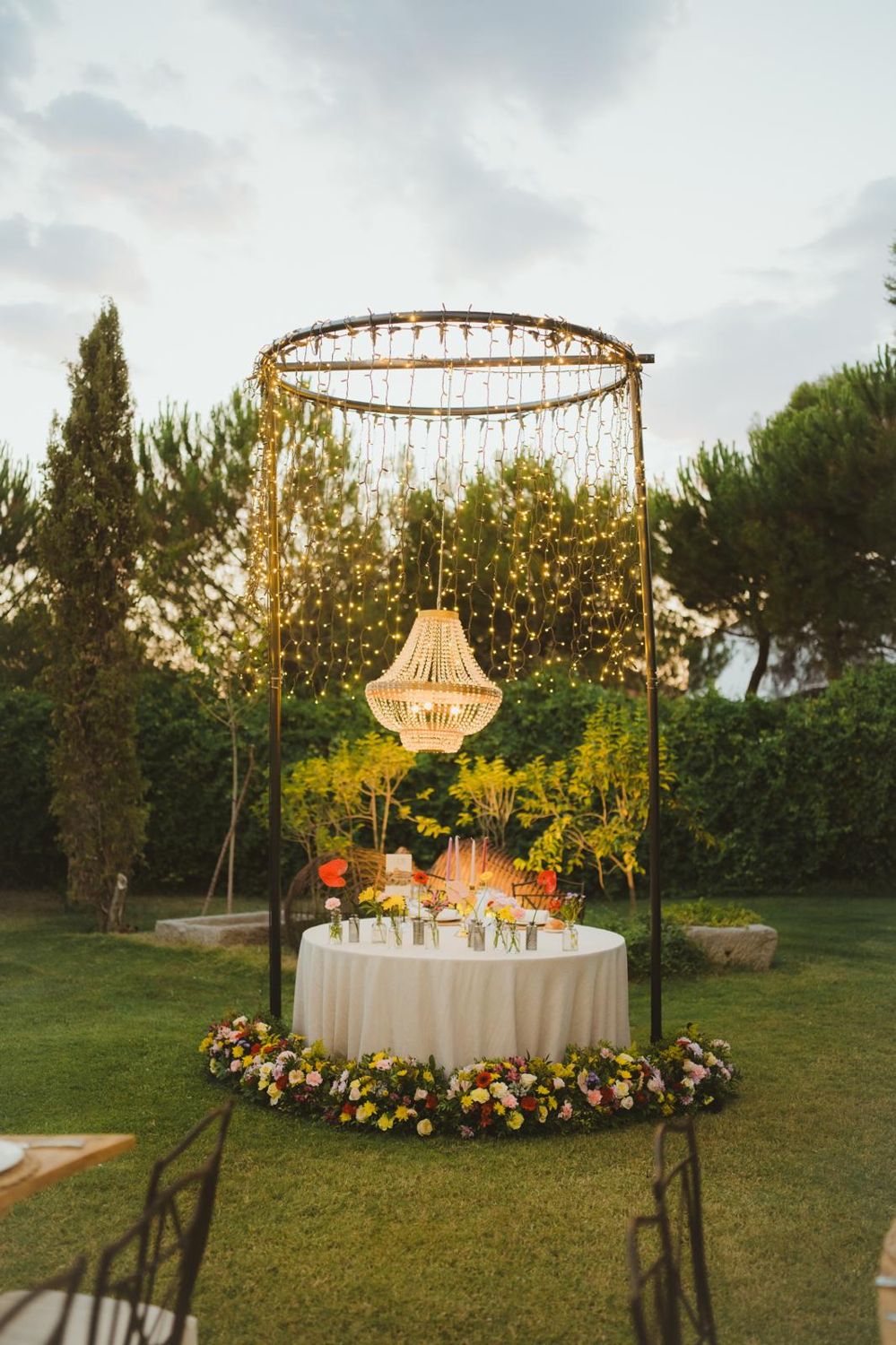 Mesa de novios con corona de flores bajo una lámpara de cristal